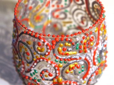 szklany świecznik w kształcie słoiczka ozdobiony wielokolorowymi kropkami farby