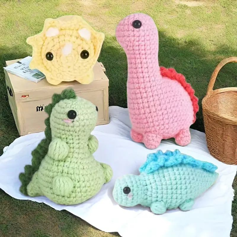 Na obrazku widać 4 maskotki obszyte metodą sztuki amigurami. Są to cztery dinozaury, każdy w innym kolorze: różowy, zielony niebieski oraz żółty.