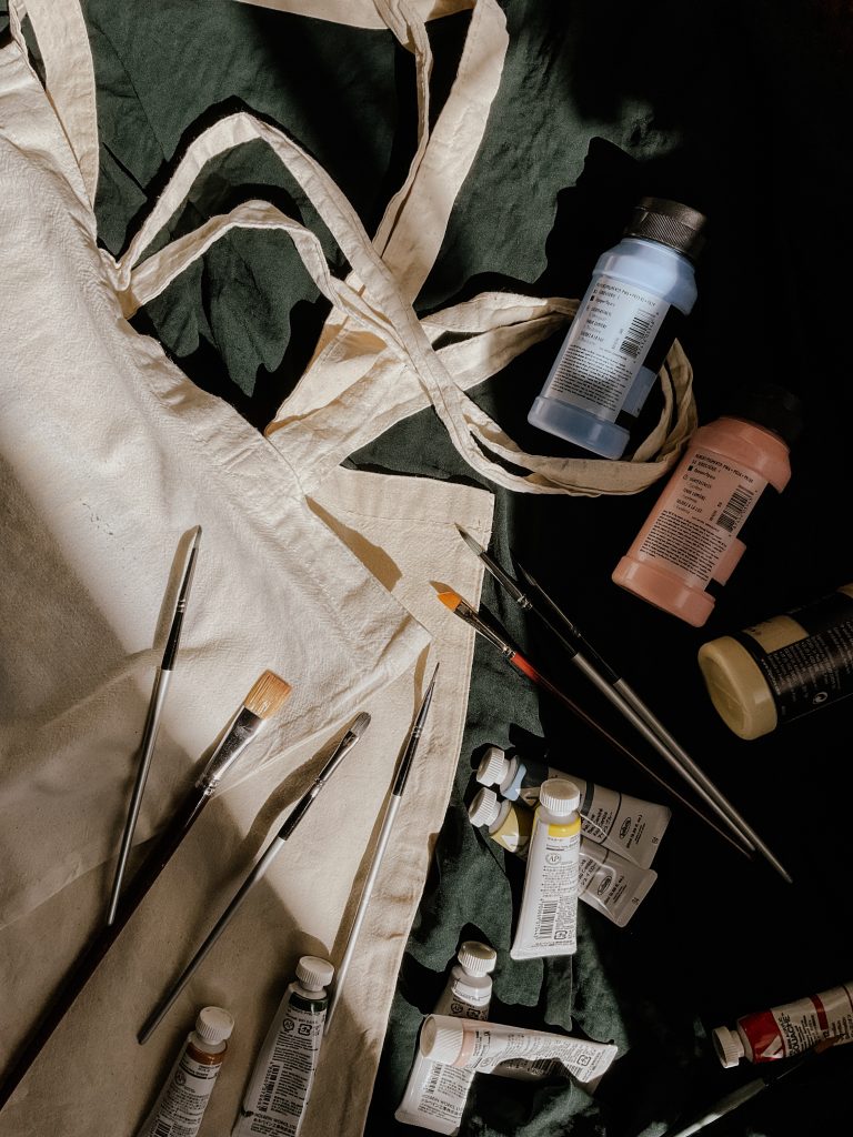 Zdjęcie przedstawia torby płócienne, farby i pędzle