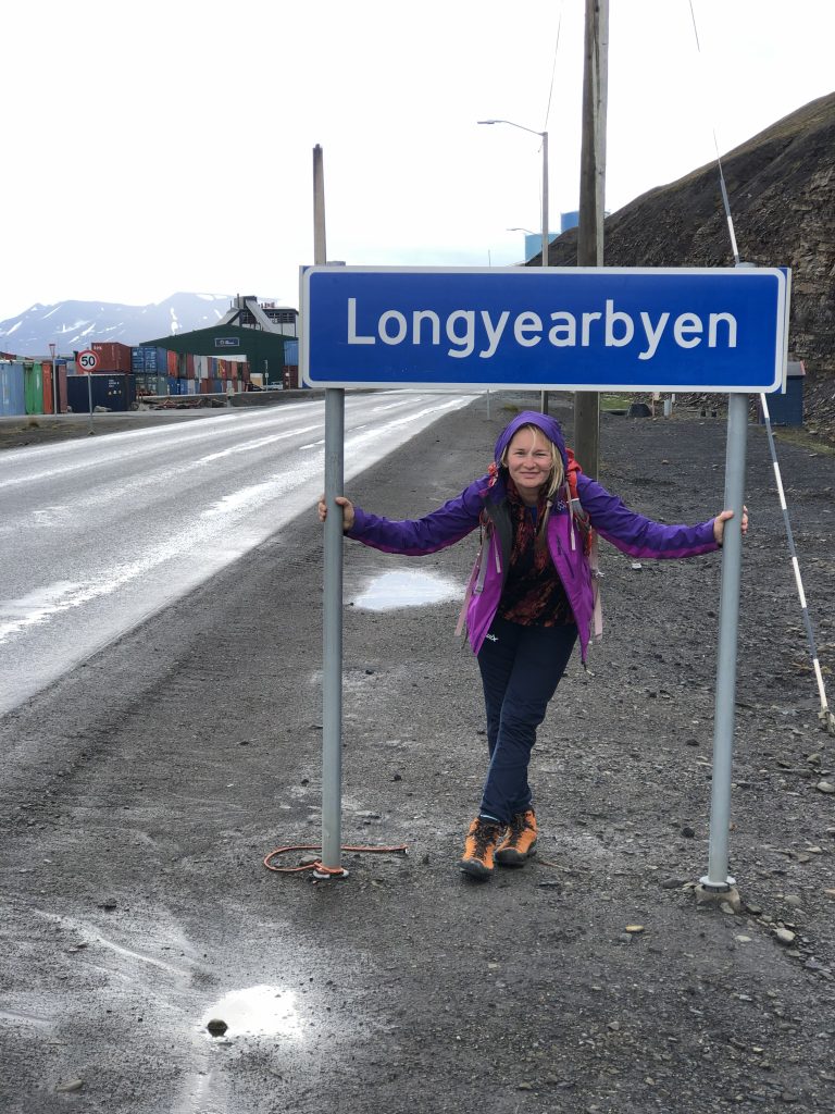 Fotografia Sylwii Kunze stojącej pod znakiem z napisem Longyearbyen.